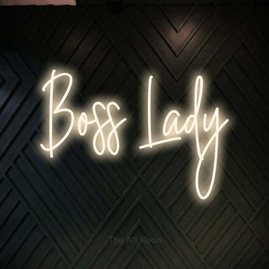 Warm white script-style LED neon sign reading "Boss Lady" against a dark geometric wood wall