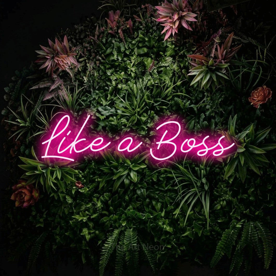 Hot pink script-style LED neon sign reading "Like a Boss" against a flowering garden wall