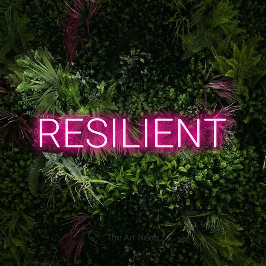 Enseigne néon à DEL à lumière rose vif, affichant « Resilient » sur un mur de jardin luxuriant aux fleurs roses