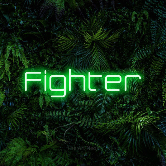 Enseigne néon à DEL à lumière verte, affichant « Fighter » sur un mur de feuillage tropical dense