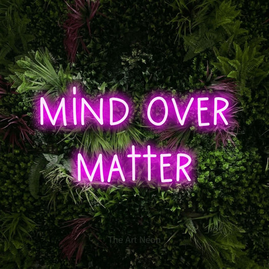 Enseigne néon à DEL à lumière rose, affichant « Mind Over Matter » sur un mur de jardin luxuriant aux fleurs roses