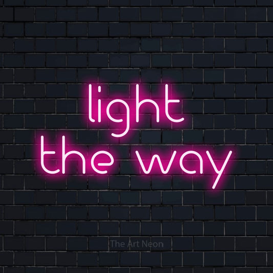 Enseigne néon à DEL à lumière rose vif, affichant « Light the Way » sur un mur de briques bleu marine foncé