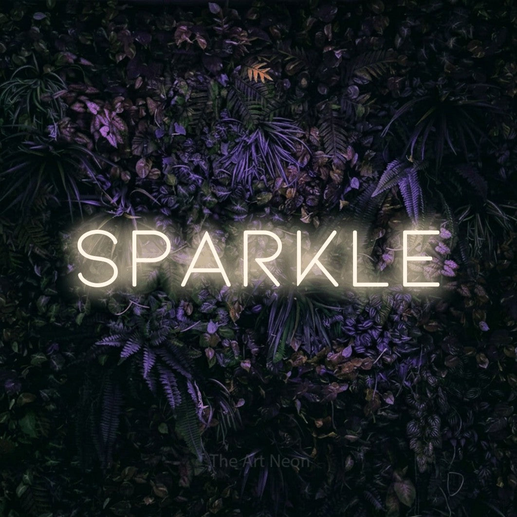 Warm white outline-style LED neon sign reading "Sparkle" against a purple floral wall