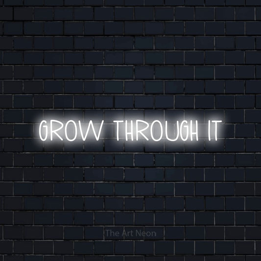 Enseigne néon à DEL à lumière blanche froide, affichant « Grow Through It » sur un mur de briques bleu marine foncé