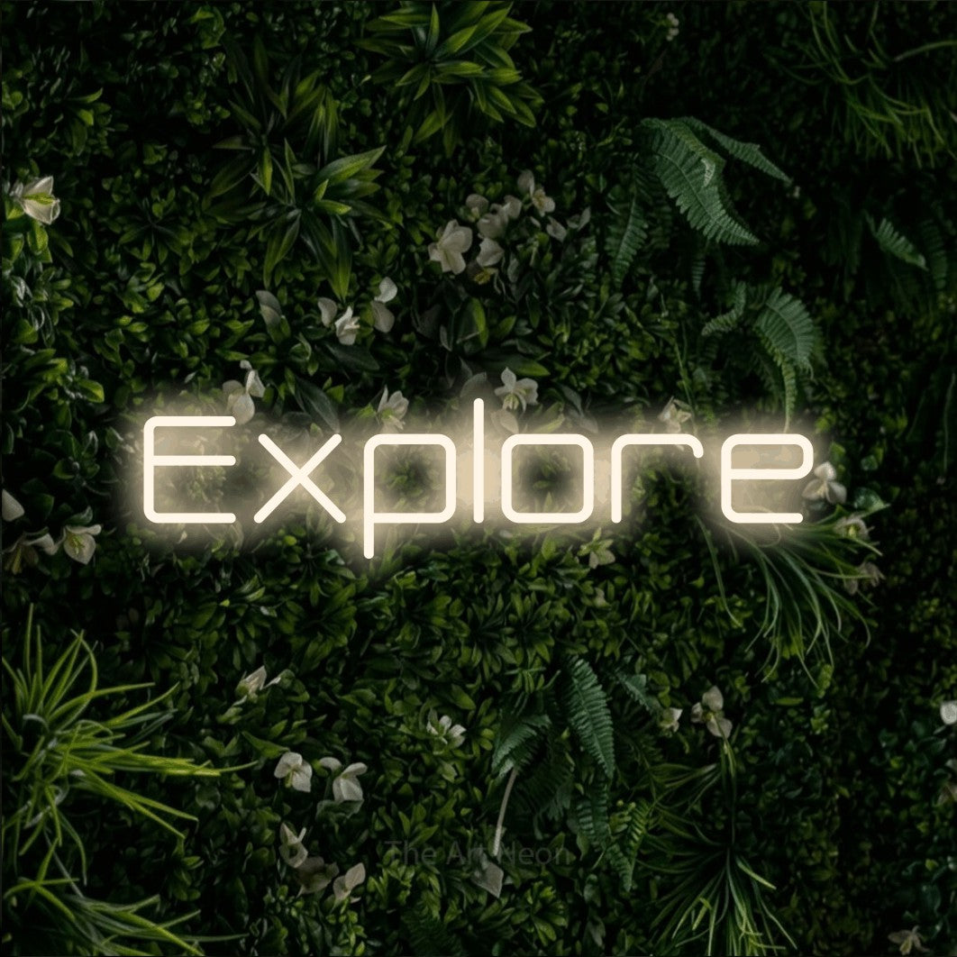 Warm white LED neon sign reading "Explore" against a leafy green wall