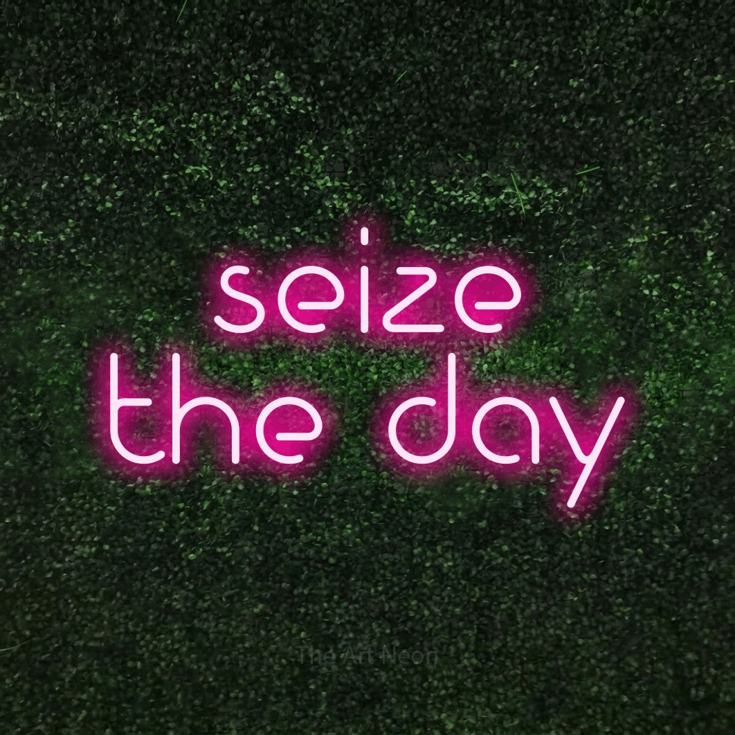 Hot pink LED neon sign reading "Seize the Day" against a textured green moss wall