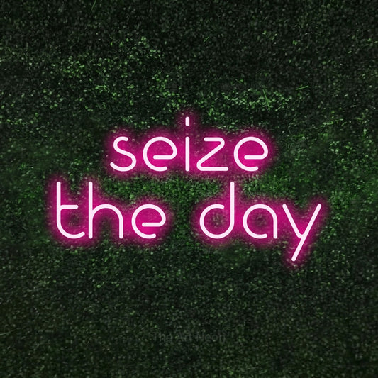 Hot pink LED neon sign reading "Seize the Day" against a textured green moss wall