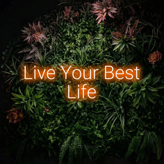 Orange LED neon sign reading "Live Your Best Life" against a flowering garden wall