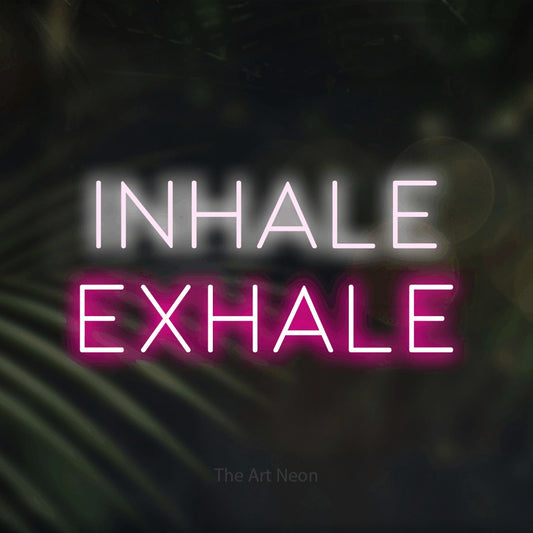 Hot pink and cool white LED neon sign reading "Inhale Exhale" against dark blurred palm leaves