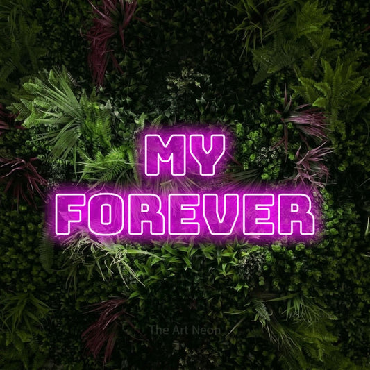 Pink outline-style LED neon sign reading "My Forever" against a lush garden wall with pink flowers