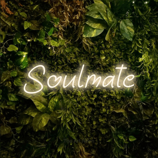 Warm white LED neon sign reading "Soulmate" against a textured moss and foliage wall