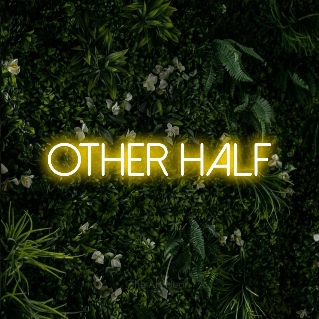 Yellow LED neon sign reading "Other Half" against a leafy green wall