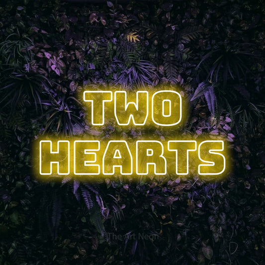 Yellow outline-style LED neon sign reading "Two Hearts" against a purple floral wall