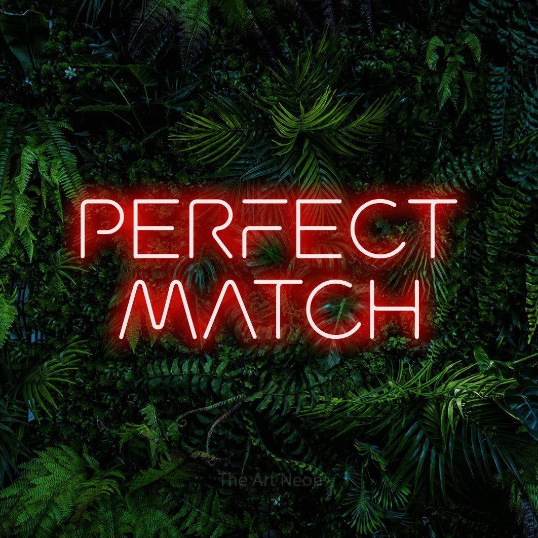 Red LED neon sign reading "Perfect Match" against a dense tropical foliage wall