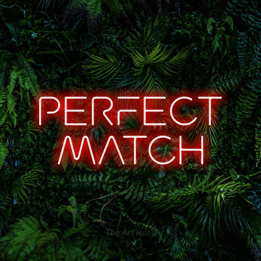 Red LED neon sign reading "Perfect Match" against a dense tropical foliage wall