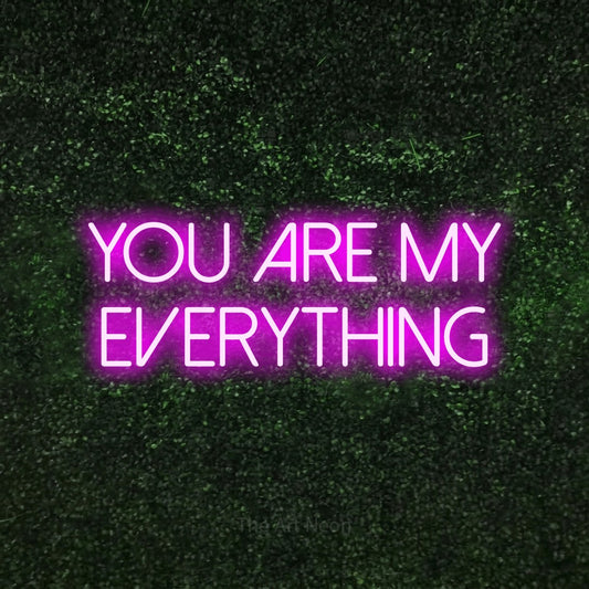 Pink LED neon sign reading "You Are My Everything" against a textured green moss wall