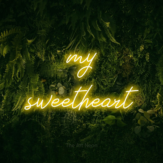 Yellow script-style LED neon sign reading "My Sweetheart" against a moss-covered green wall