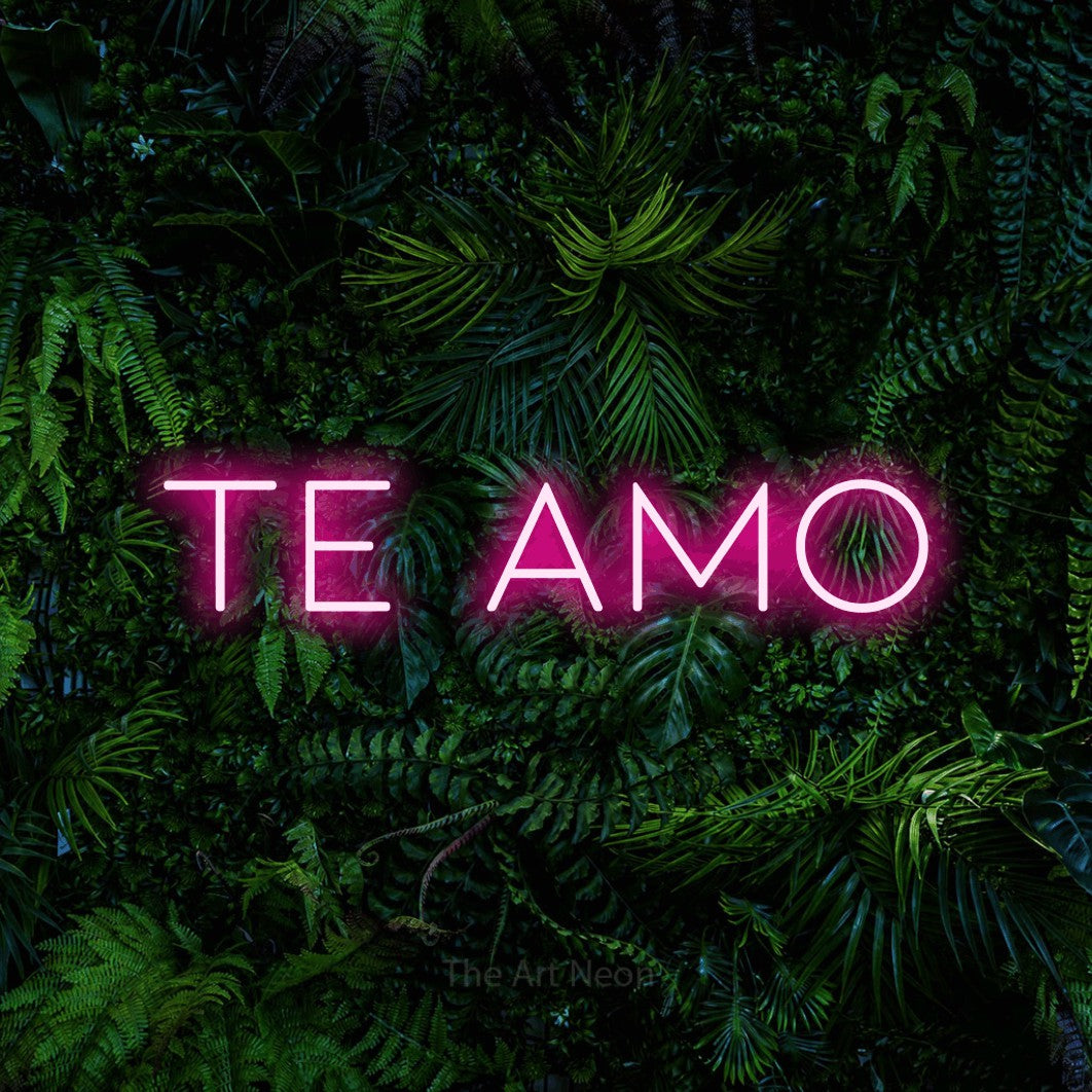 Hot pink LED neon sign reading "Te Amo" against a dense tropical foliage wall
