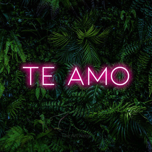 Hot pink LED neon sign reading "Te Amo" against a dense tropical foliage wall