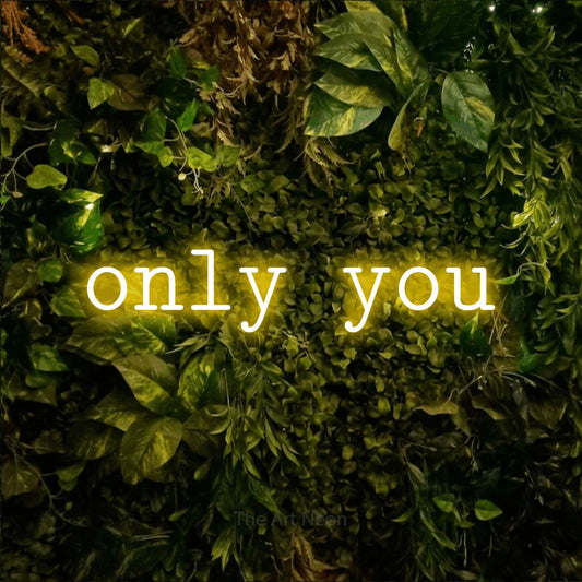 Yellow LED neon sign reading "Only You" against a textured moss and foliage wall