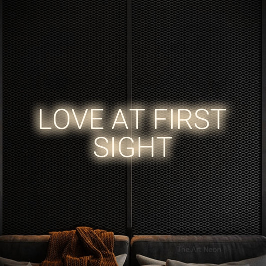 Warm white LED neon sign reading "Love at First Sight" against a black textured wall