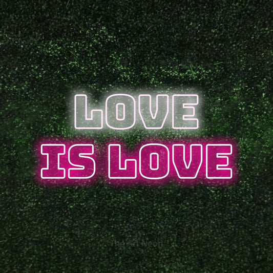 Hot pink and cool white outline-style LED neon sign reading "Love is Love" against a textured green moss wall
