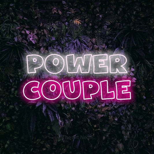 Hot pink and cool white outline-style LED neon sign reading "Power Couple" against a purple floral wall