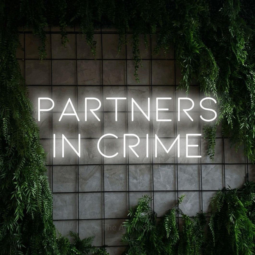 Cool white LED neon sign reading "Partners in Crime" against a green grid wall with foliage