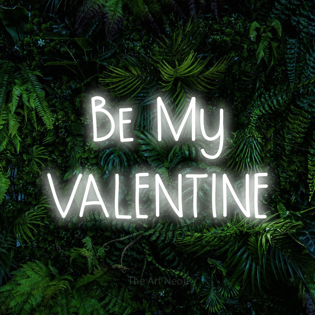 Cool white LED neon sign reading "Be My Valentine" against a dense tropical foliage wall