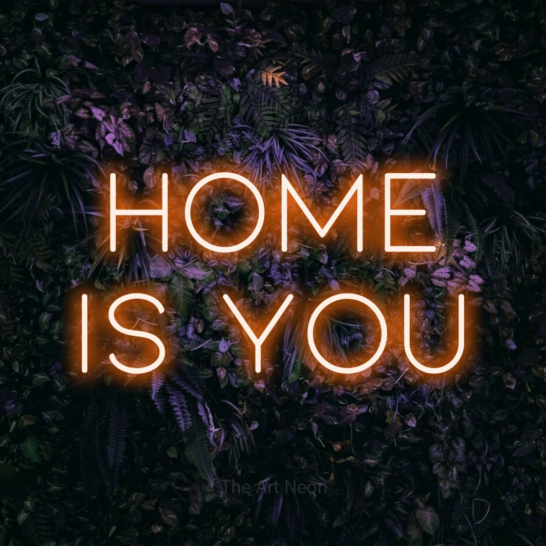 Orange LED neon sign reading "Home is You" against a purple floral wall