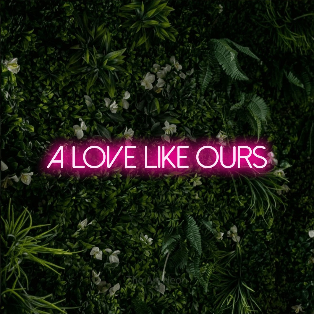 Hot pink LED neon sign reading "A Love Like Ours" against a leafy green wall
