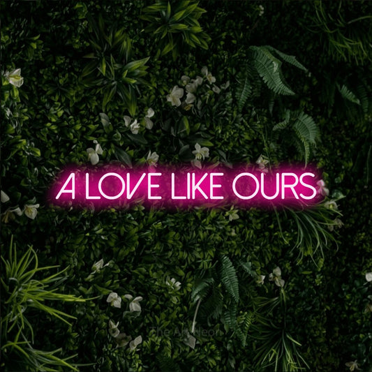 Hot pink LED neon sign reading "A Love Like Ours" against a leafy green wall