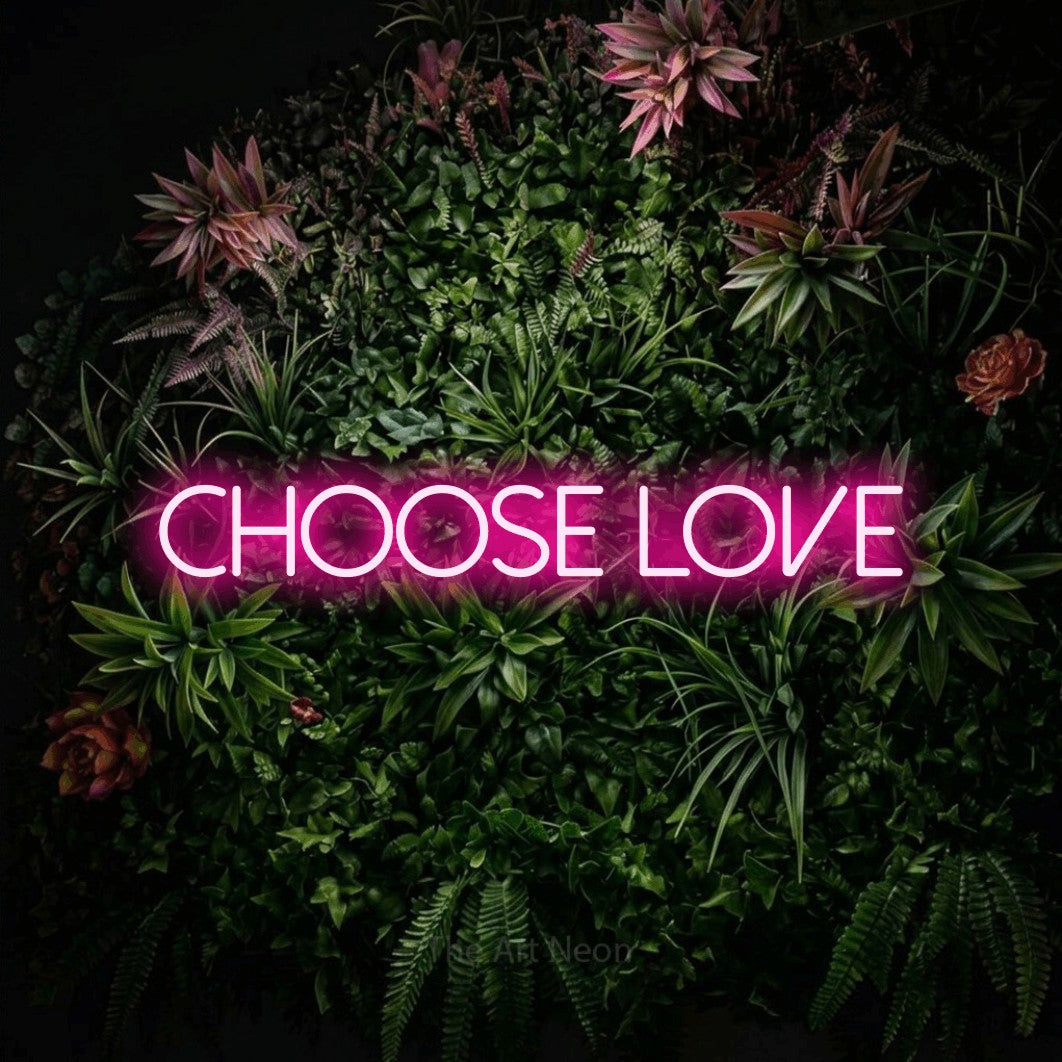 Hot pink LED neon sign reading "Choose Love" against a flowering garden wall