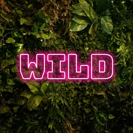 Hot pink outline-style LED neon sign reading "Wild" against a textured moss and foliage wall