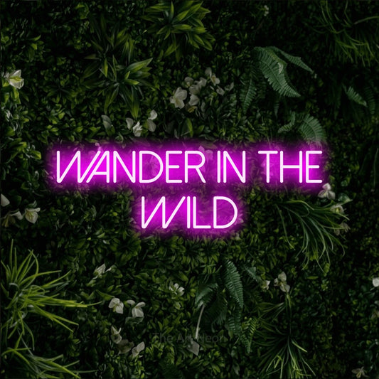 Pink LED neon sign reading "Wander in the Wild" against a leafy green wall