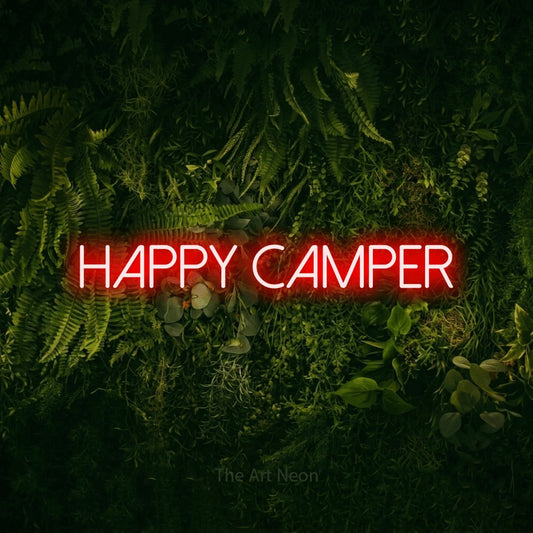 Red LED neon sign reading "Happy Camper" against a moss-covered green wall