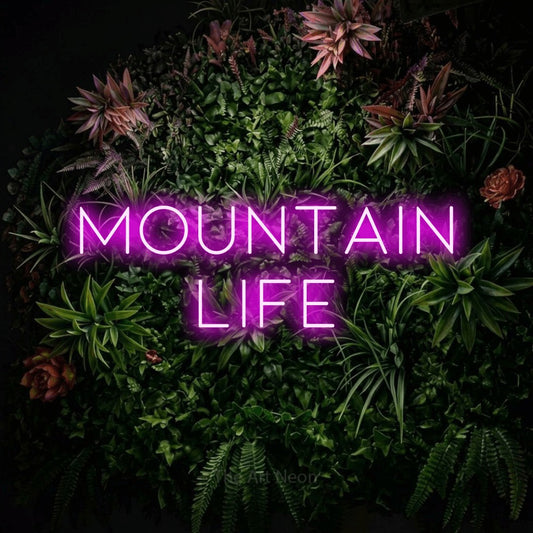 Pink LED neon sign reading "Mountain Life" against a flowering garden wall