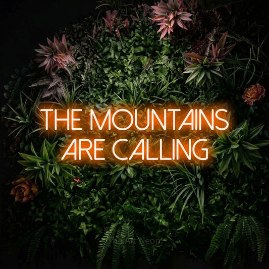 Orange LED neon sign reading "The Mountains Are Calling" against a flowering garden wall