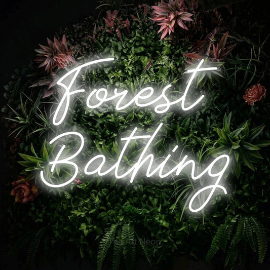 Cool white script-style LED neon sign reading "Forest Bathing" against a flowering garden wall