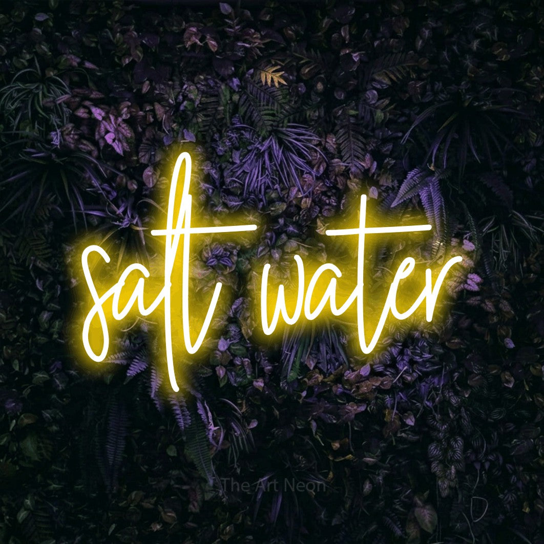 Yellow script-style LED neon sign reading "Salt Water" against a purple floral wall