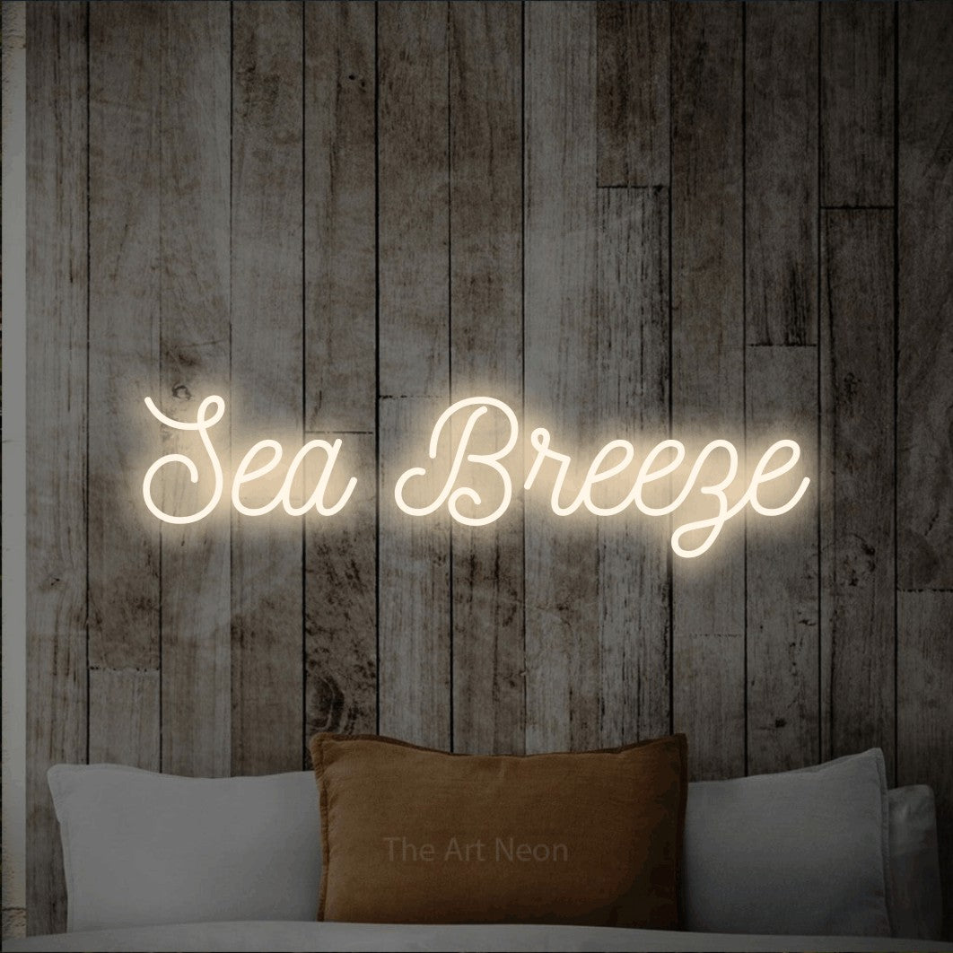 Warm white script-style LED neon sign reading "Sea Breeze" against a whitewashed wooden wall