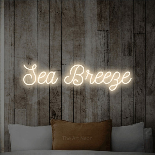 Warm white script-style LED neon sign reading "Sea Breeze" against a whitewashed wooden wall