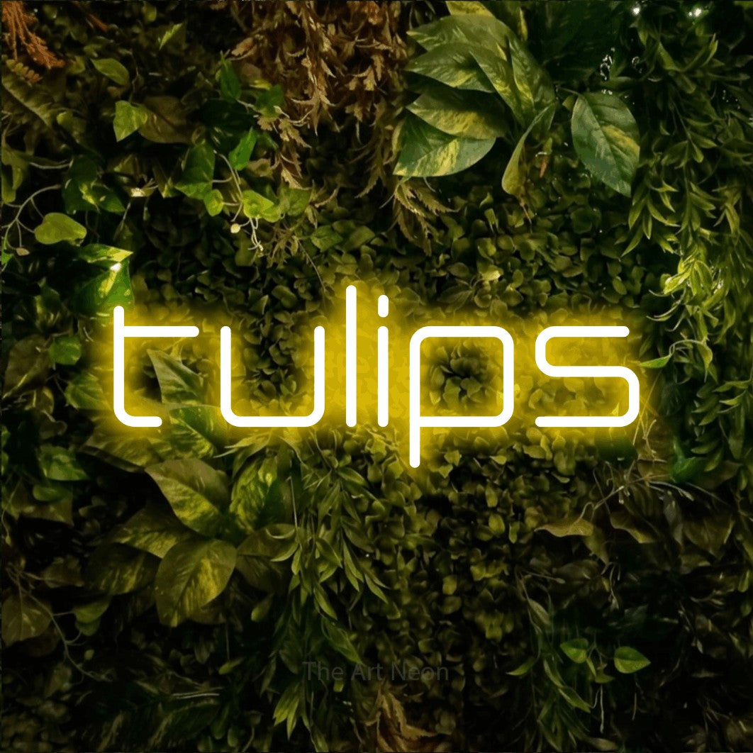 Yellow LED neon sign reading "Tulips" against a textured moss and foliage wall