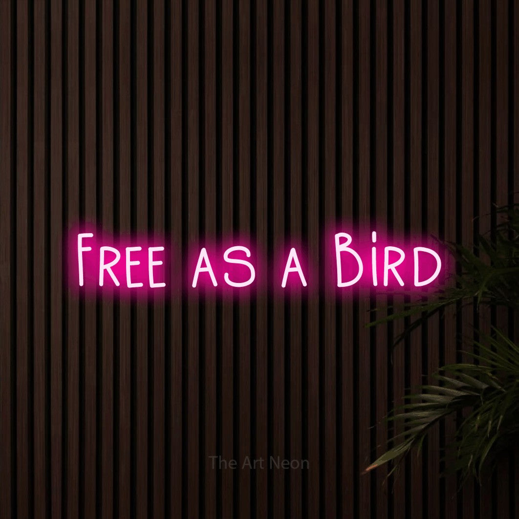 Hot pink LED neon sign reading "Free as a Bird" against dark wooden slats