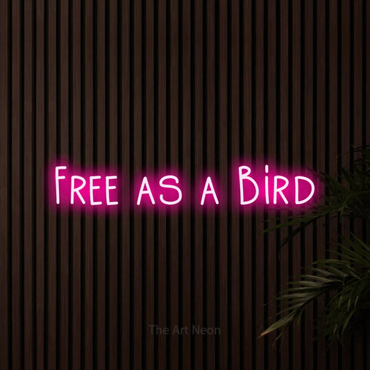 Hot pink LED neon sign reading "Free as a Bird" against dark wooden slats