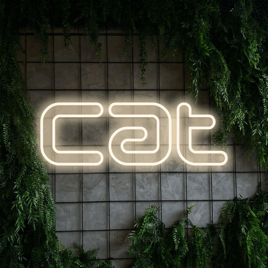 Warm white outline-style LED neon sign reading "Cat" against a green grid wall with foliage
