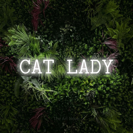 Cool white LED neon sign reading "Cat Lady" against a lush garden wall with pink flowers