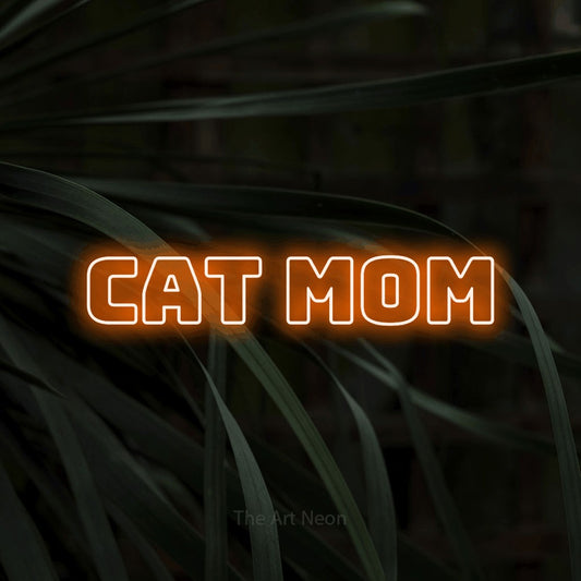 Orange outline-style LED neon sign reading "Cat Mom" against dark tropical leaves