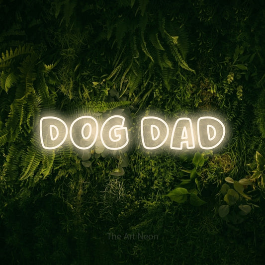 Warm white outline-style LED neon sign reading "Dog Dad" against a moss-covered green wall