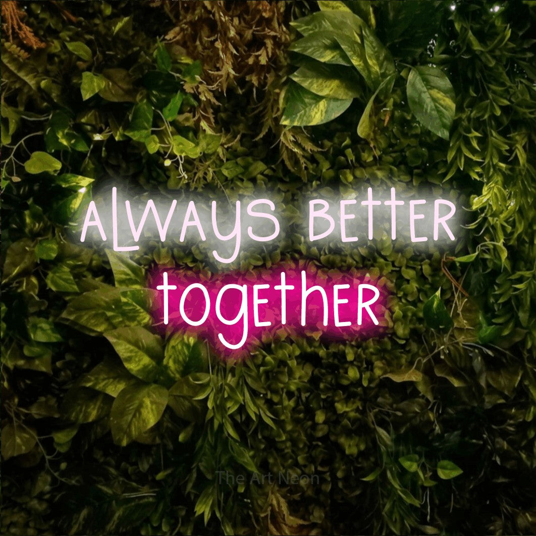Hot pink and cool white LED neon sign reading "Always Better Together" against a textured moss and foliage wall